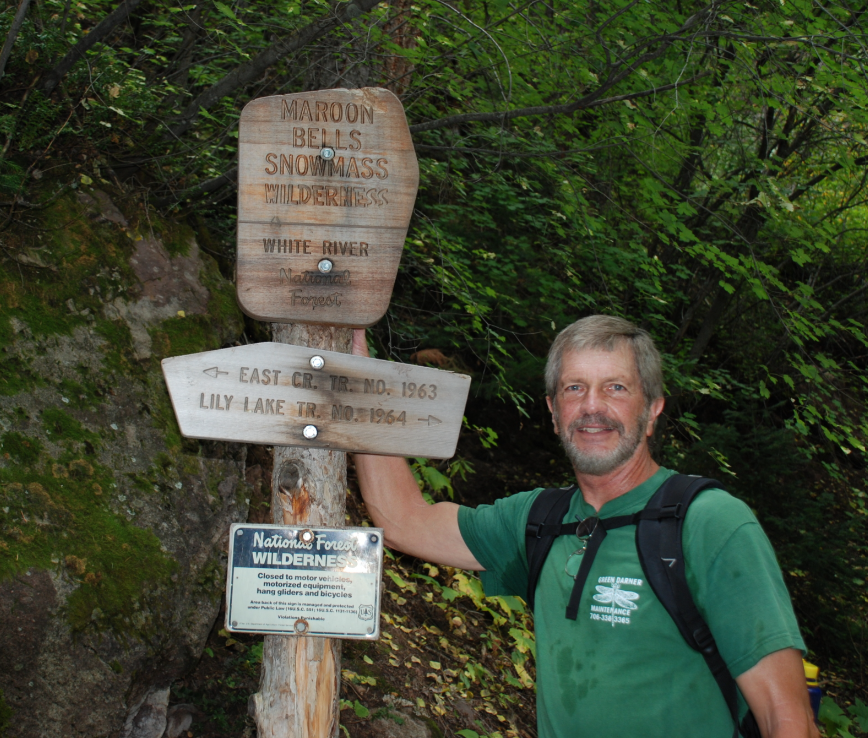 Ken standing by an entrance to a hiking post
