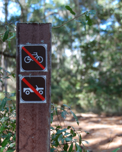 A small hiking sign showing no motorized vehicles are allowed on the trail