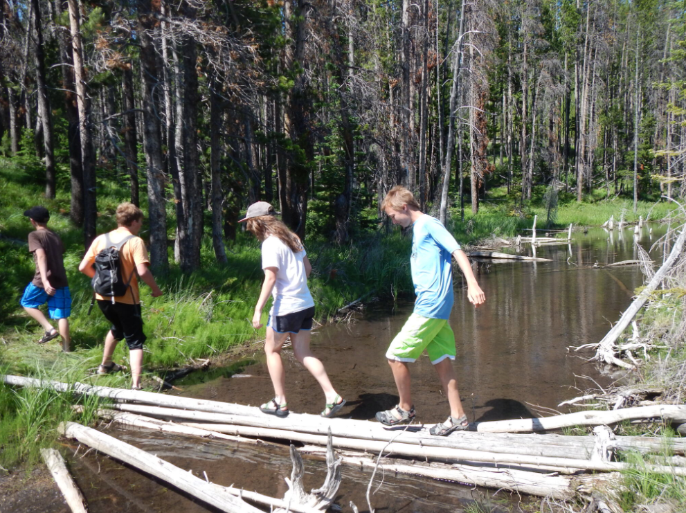 People hiking waling over a stream