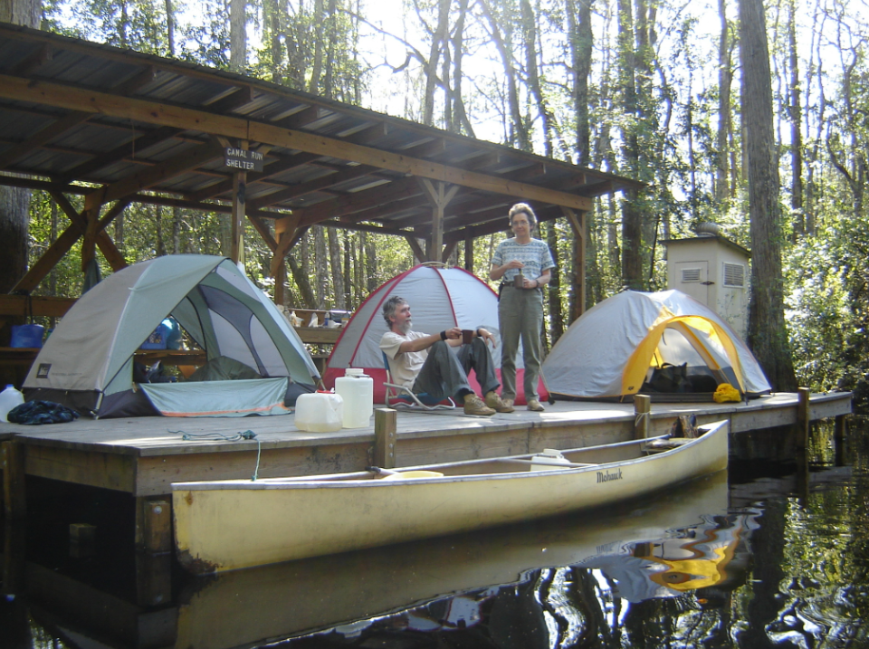 Tents set up on a wooden platform with a canoe infront