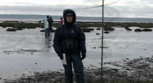 A person in a jacket standing in front of a body of water