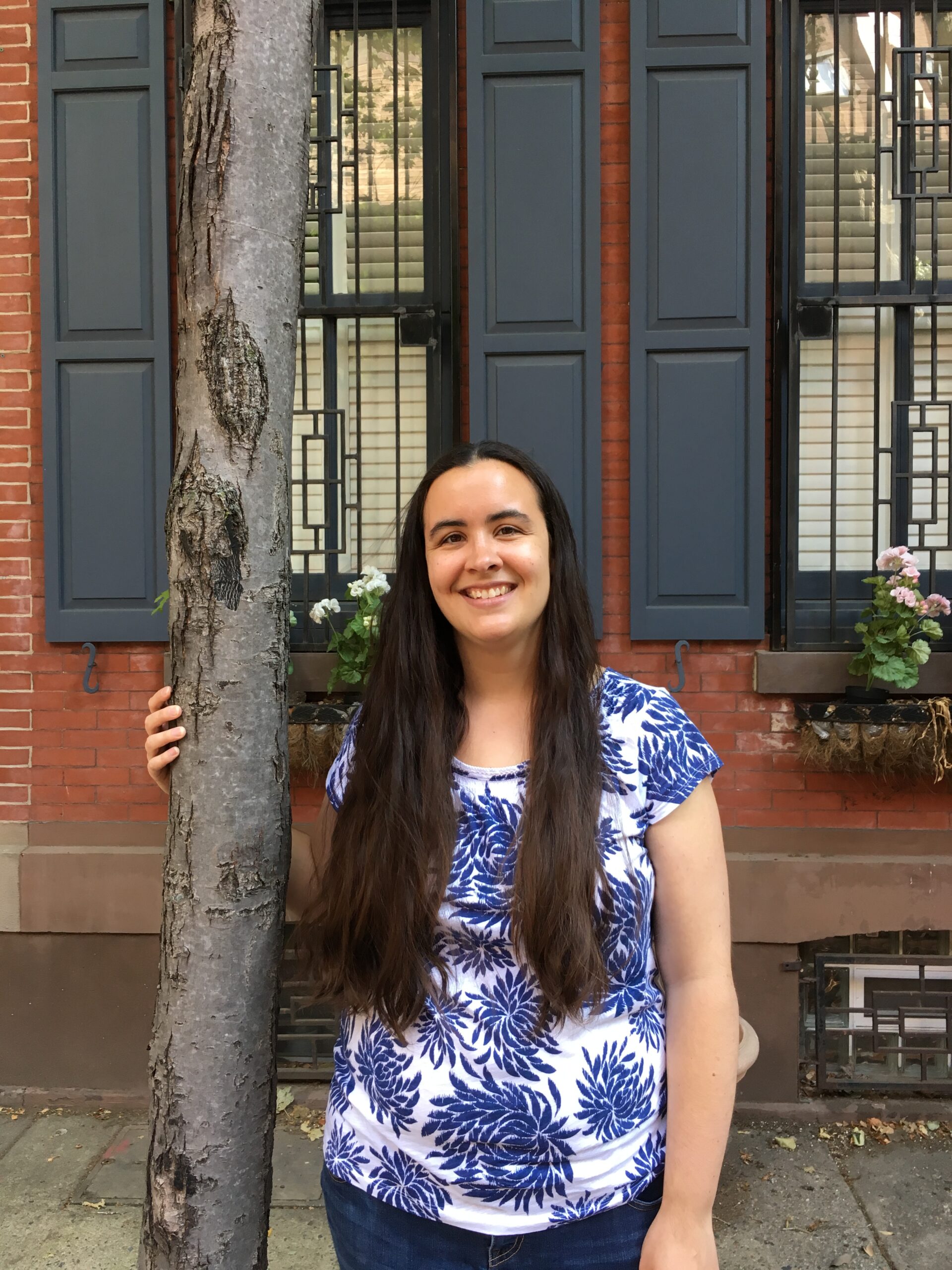 Dr. Lara Roman in an urban area standing next to a street tree