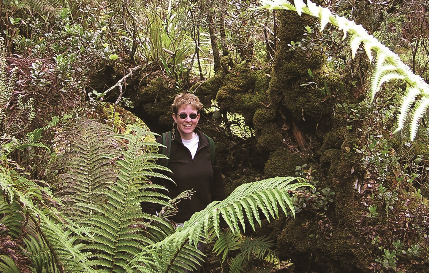 Dr. Debbie Page-Dumroese walking through a green forest.