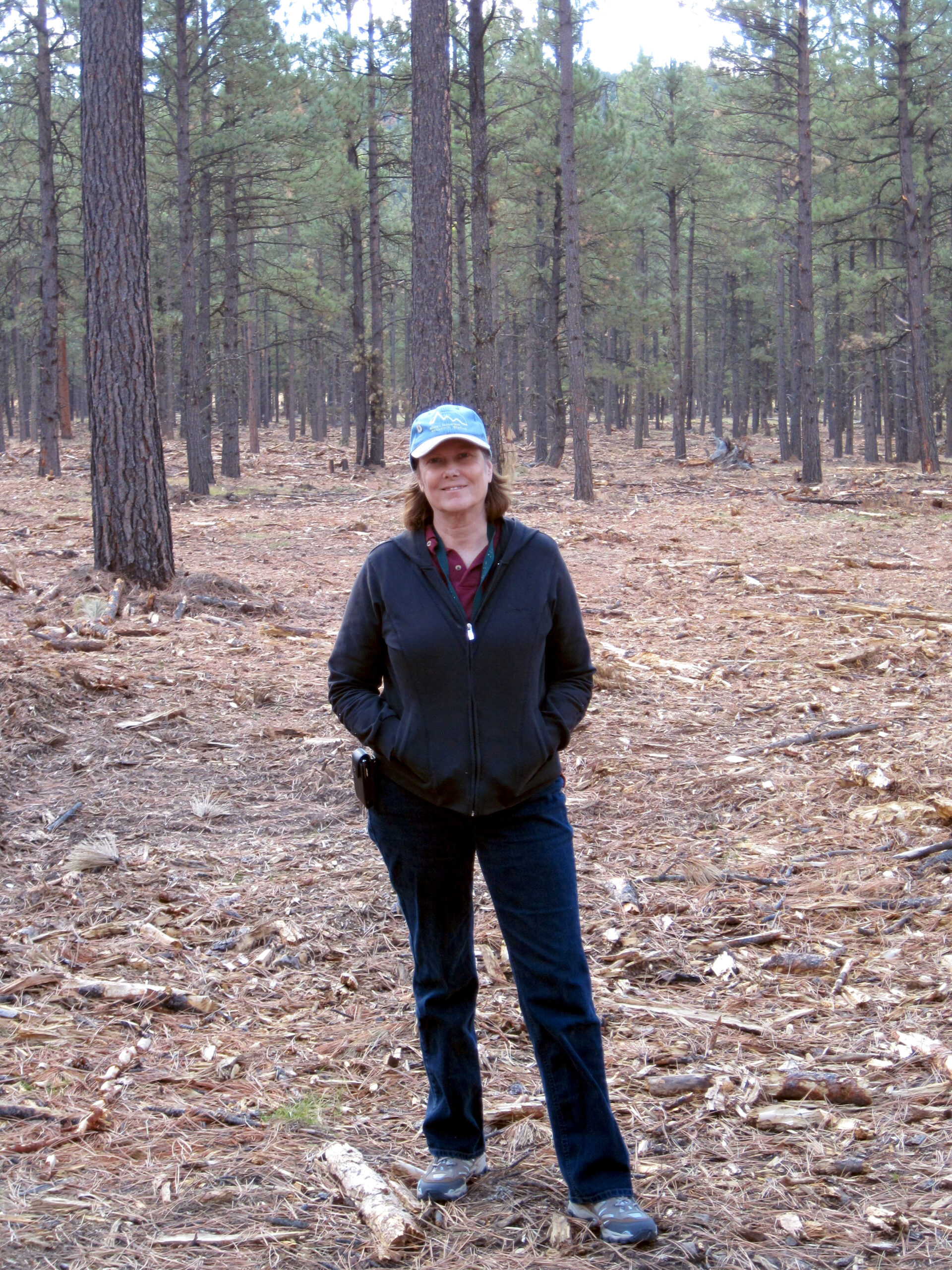 Photo of Deborah Finch standing in a forest.