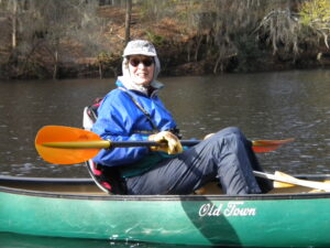 Photo of Katherine Ewel sitting in a canoe and holding a paddle.