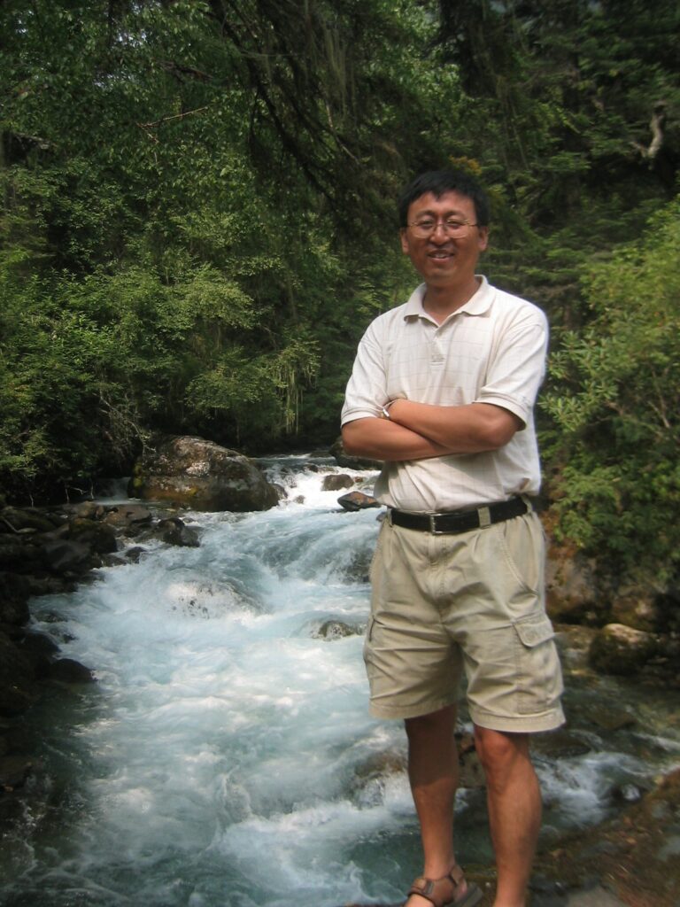 Dr. Ge Sun standing in front of rapids and trees