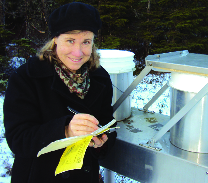 Adelaide Johnson takes notes outside next to an experimental setup.