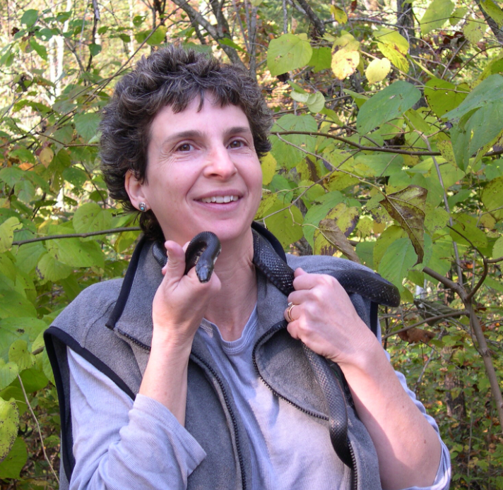 Cathryn Greenberg stands outside and holds a black snake around her neck.