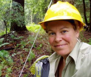 Claudia Cotton wears a yellow hard hat in a forest.