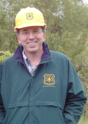David Bengston wears a yellow hard hat outside.