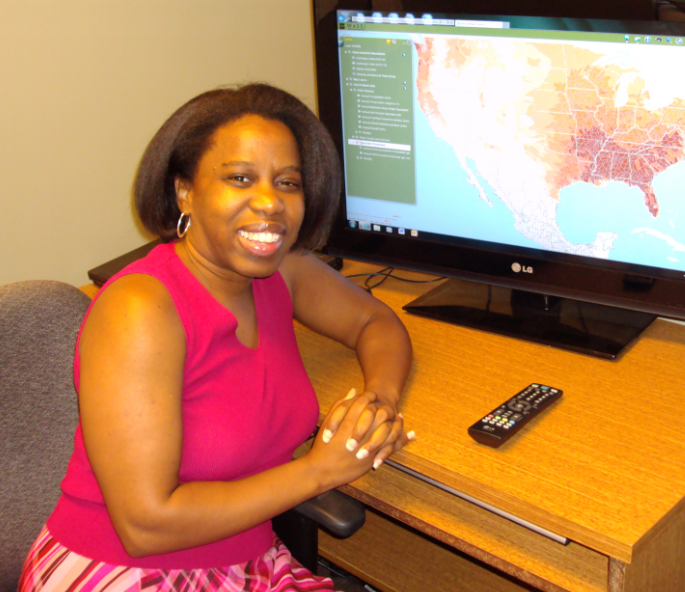 Erika Cohen sits at a computer that displays a map of the U.S.