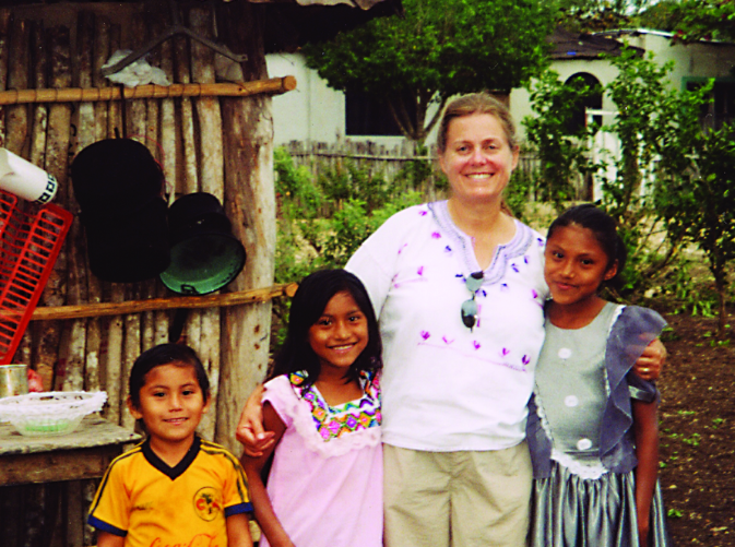 Marla Emery and three children outside a wooden building.