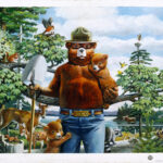 Smokey Bear painting with Smokey Bear holding a shovel in one arm and holding a baby bear in another arm. Behind Smokey bear is a woodland scene.