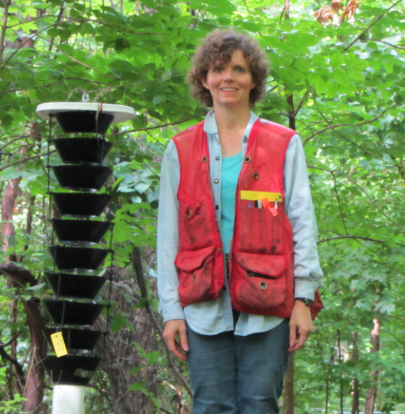 Therese Poland stands in the forest next to insect traps.