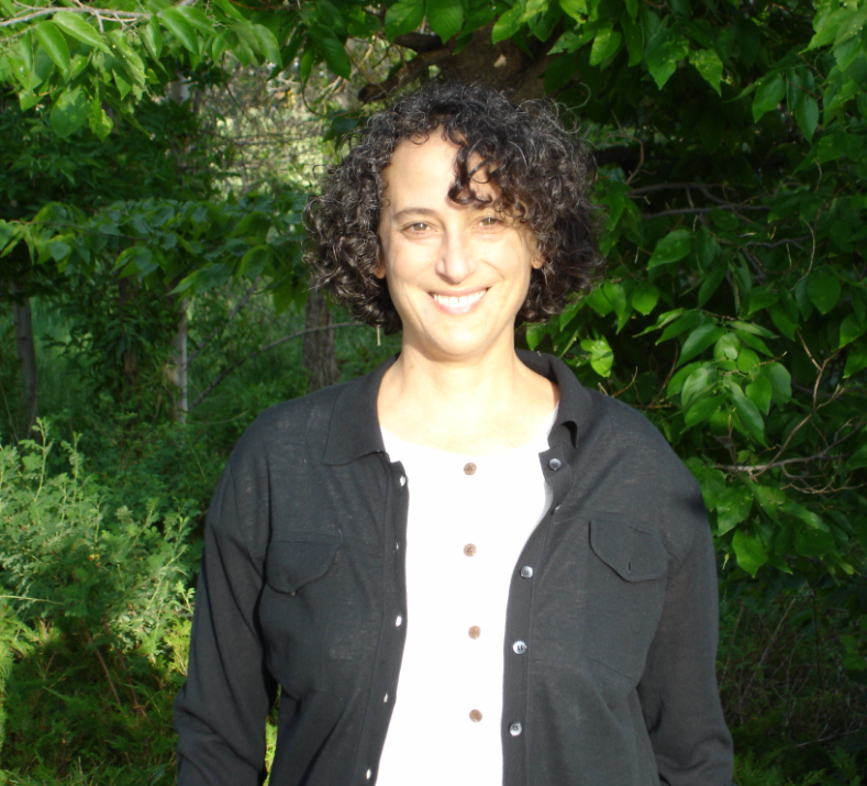 Eileen Helmer stands in front of trees.