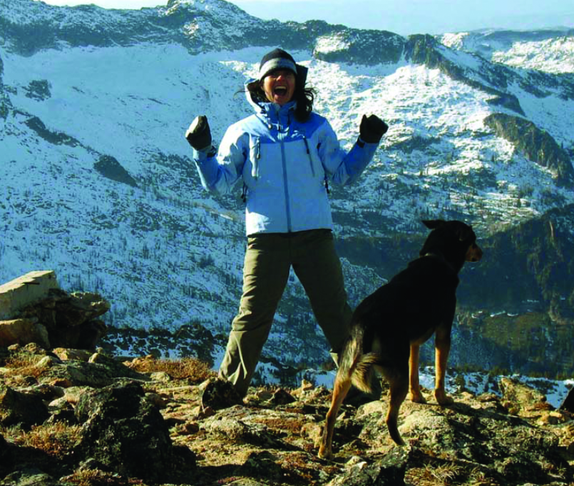 Yvette Ortega stands on top of a mountain with her dog