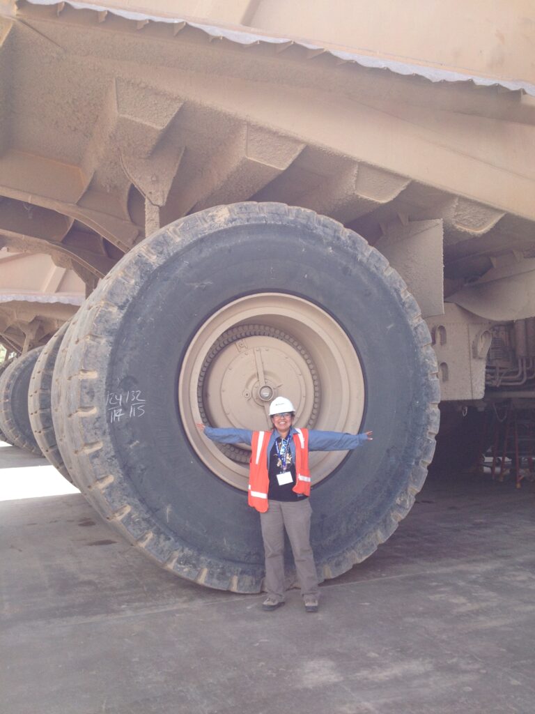 Frances Alvarado in front of a large machine wheel
