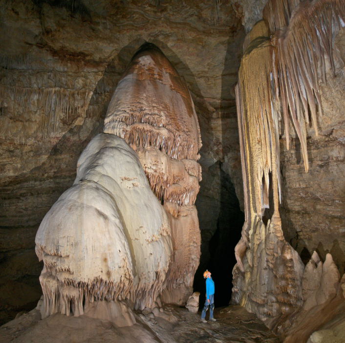 A person looking up at several different cave formations