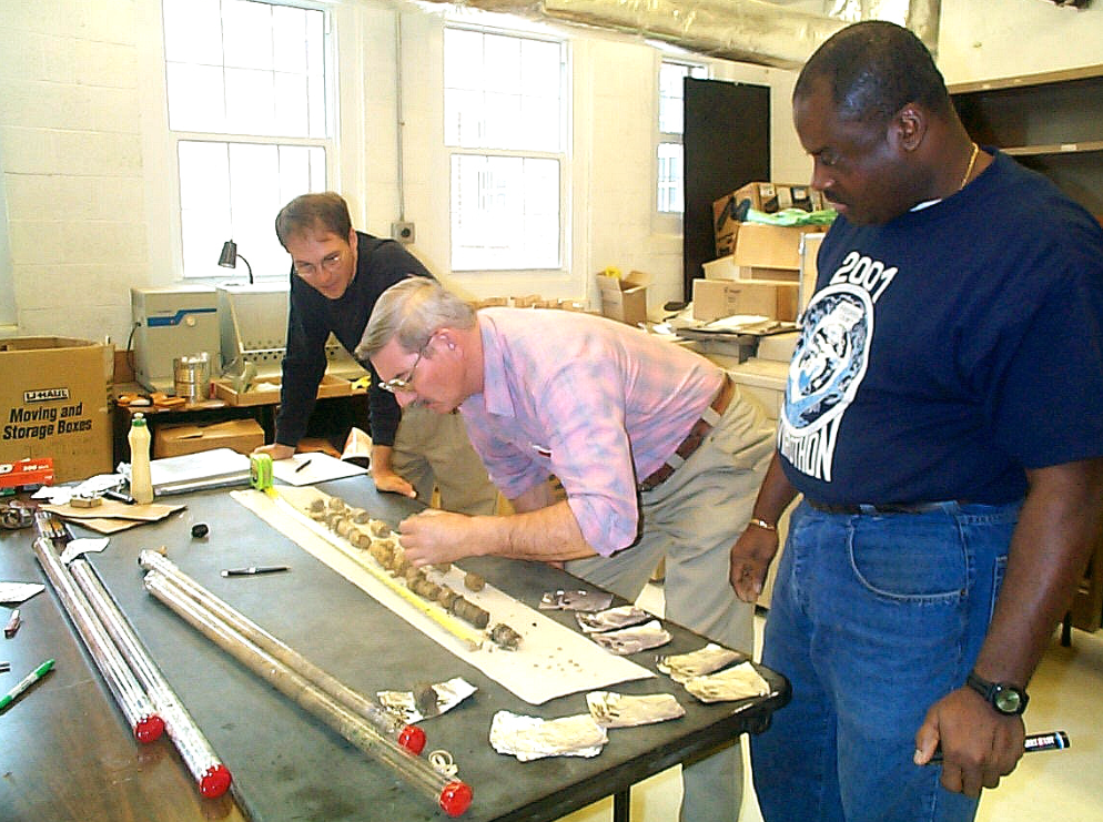 3 scientists examining soil samples on a lab table
