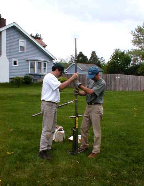 Two scientist using an instrument to take a soil sample