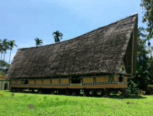 A Palauan long house with a thatched roof and decoratively painted walls
