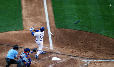 A baseball player swinging a broken bat at home base