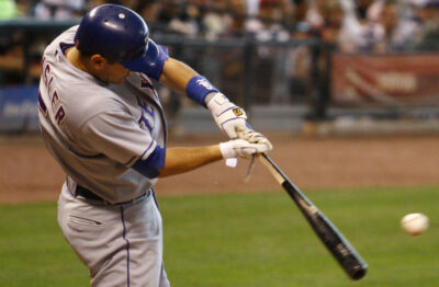 A close up of a batter swinging a broken bat at a baseball