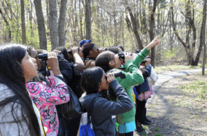 Kids using binoculars outside and pointing at something