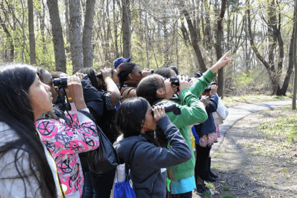 Kids using binoculars outside and pointing at something