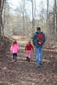 two children and an adult hiking in the woods