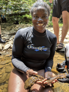 Dr. Barnett kneels in a stream bed and holds a hellbender