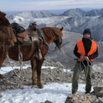 Ellie Fitzpatrick on the top of a mountain leading two horses