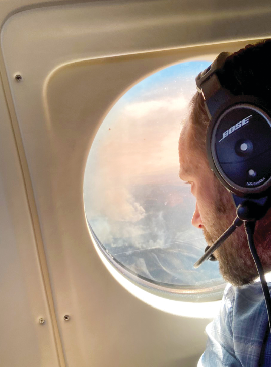 Mr. Atkins wears a headset and looks out a plane window