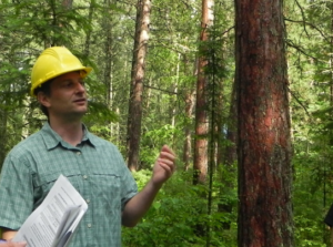 Chris Swanston outside in the foerst wearing a hard hat
