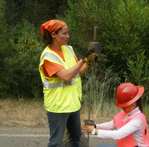 Ms. Boak wears a safety vest and works on a road