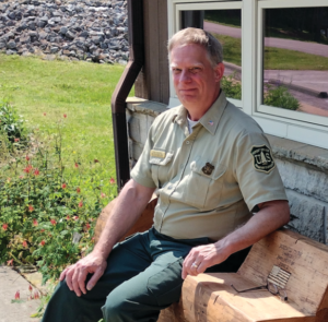 Mr. Hughes sits on a bench outside a visitor center.