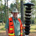 Dan Miller in protective gear next to an insect trap