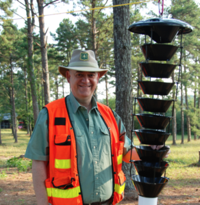 Dan Miller in protective gear next to an insect trap