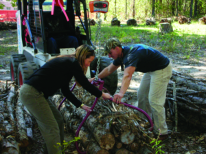 Dana and a coworker using machinery to lift a large pile of wood