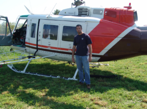 Derek Puckett in front of a helicopter