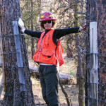 Dr. Kerns stands with her arms outstretched between two trees.