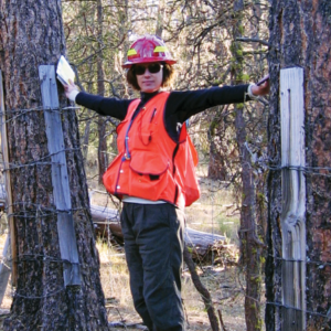 Dr. Kerns stands with her arms outstretched between two trees.