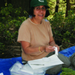 Dr. Minocha sits on a blue tarp in a forest and processes samples.