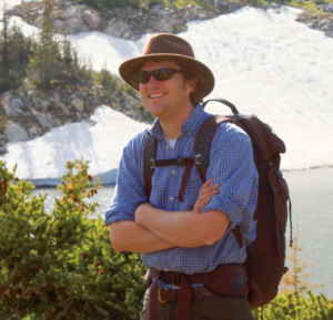 Dr. Frank wears a backpack and hat outside