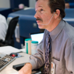Mr. LaBrode sits at his desk at Mission Control Center at NASA's Johnson Space Center.