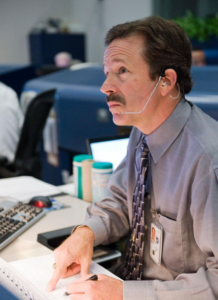 Mr. LaBrode sits at his desk at Mission Control Center at NASA's Johnson Space Center.