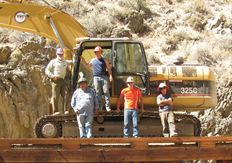 Mr. Balen stands with a crew beside an excavator