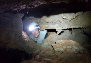 Grace Bombulum in a cave with a head lamp