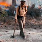 Jordan Gulley in fire protective gear holding an ax outside