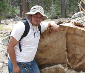 Jose Sanchez standing next to a large fallen tree